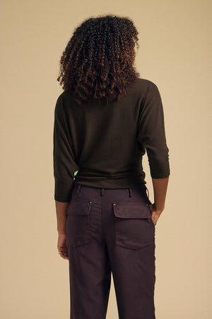 A person seen from the back wearing a dark green CECILIA TOP with dolman sleeves and dark cargo pants.