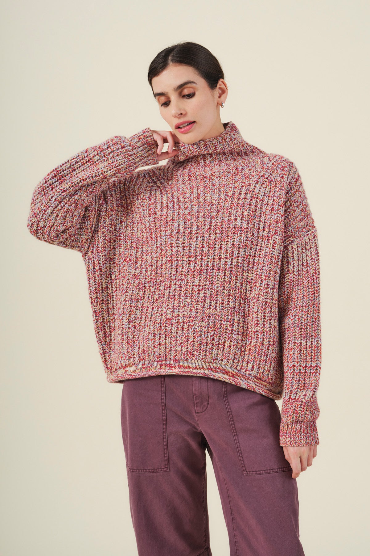Wearing the DENNIE SWEATER by Velvet by Graham & Spencer—a chunky, multicolored wool blend turtleneck with a loose fit—paired with purple pants and set against a plain light background.-41970979242177