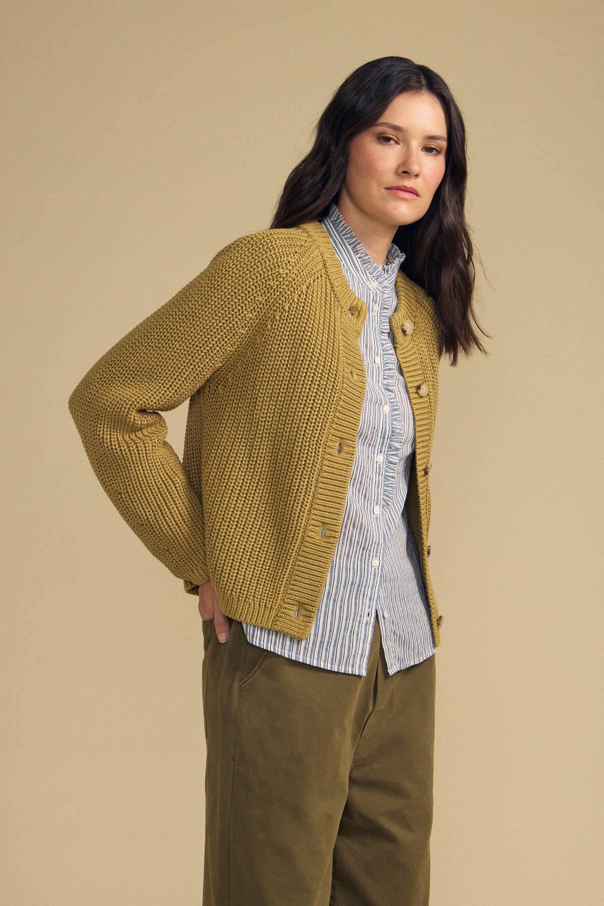 Three-quarter view of khaki LISABETH cardigan, a chunky pima cotton button front style with cropped fit, beige background