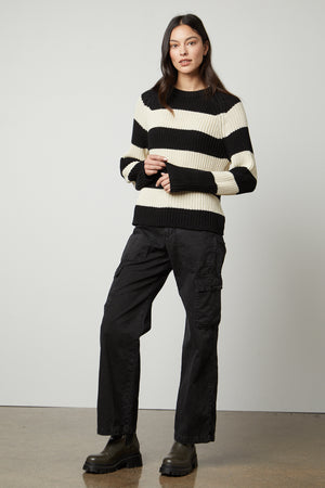 The model is wearing a Velvet by Graham & Spencer CIARA STRIPED CREW NECK SWEATER, providing warmth and comfort.