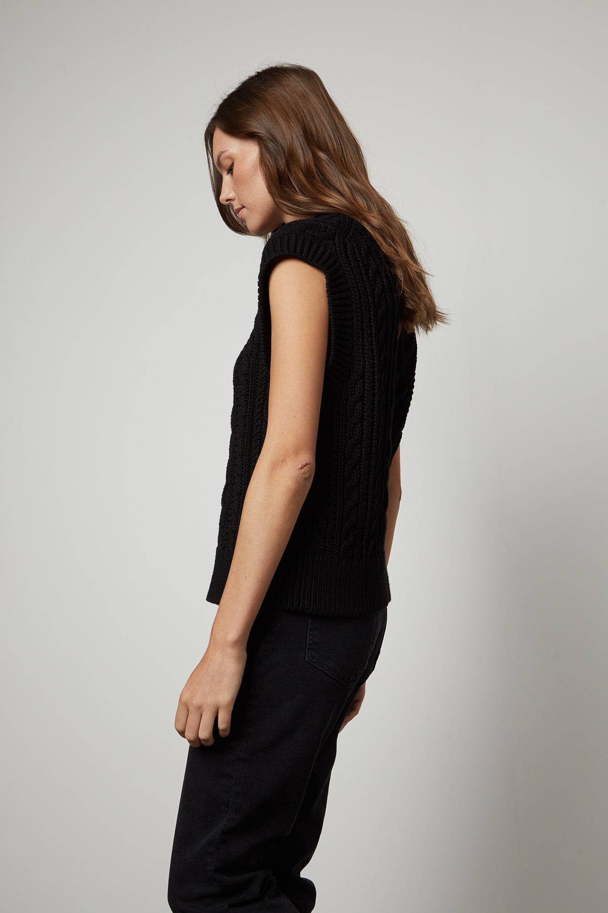 The back view of a woman wearing a Velvet by Graham & Spencer HADDEN SWEATER VEST and jeans.-26799841247425
