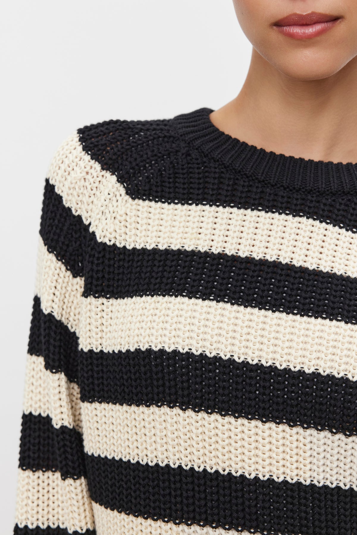   A person wearing the OLLIE SWEATER, a black and white striped knit sweater made from chunky pima cotton by Velvet by Graham & Spencer. 