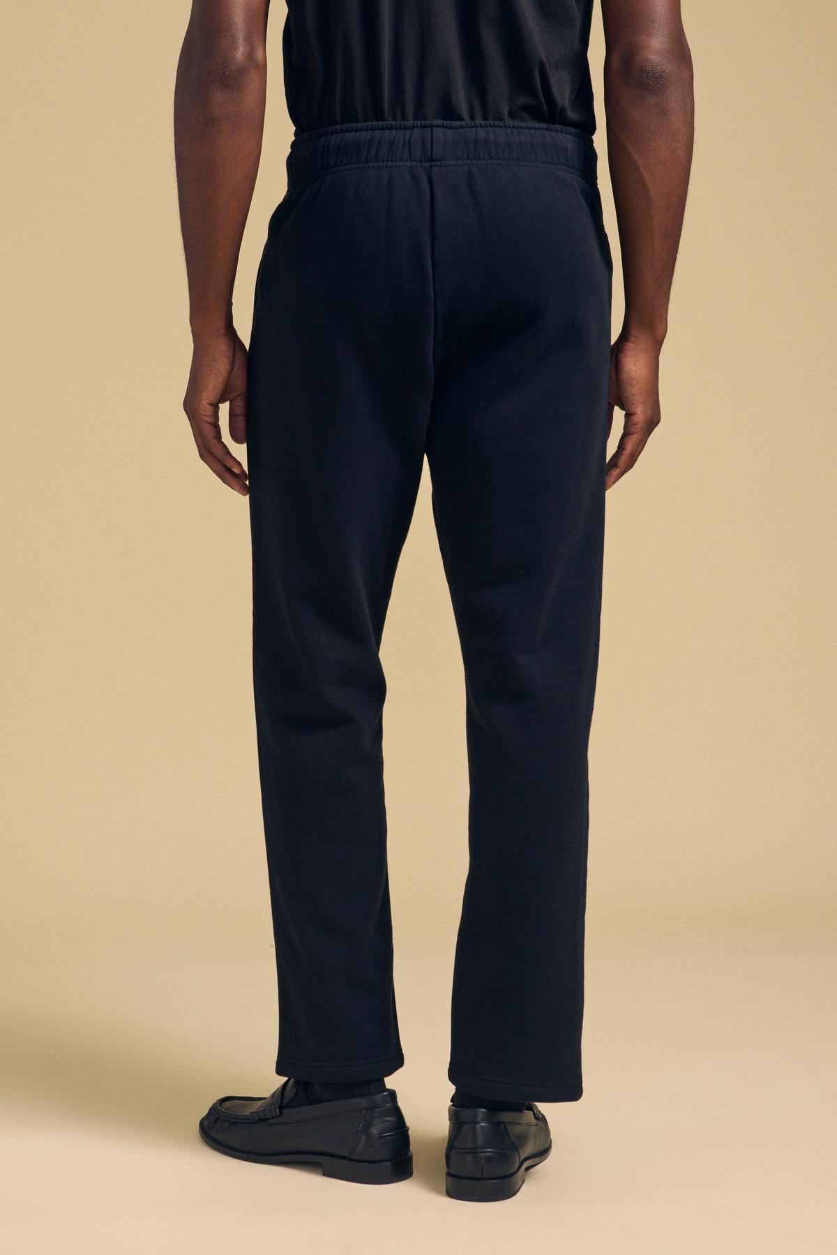 Back view of a person wearing black HUDSON SWEATPANT relaxed fit sweatpants and black loafers.-46288484925633