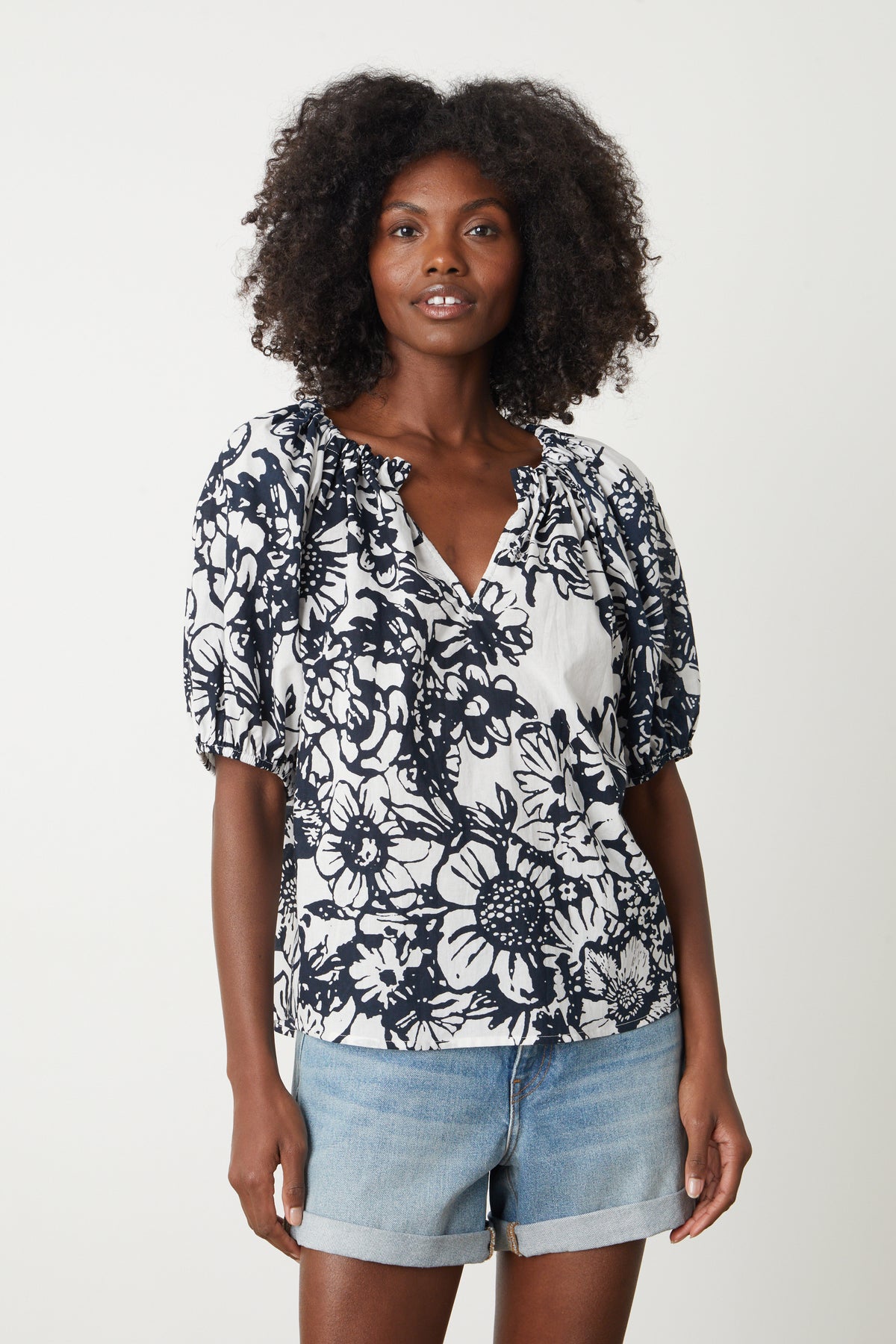   The model is wearing an ANGELA PRINTED BOHO TOP by Velvet by Graham & Spencer and denim shorts 