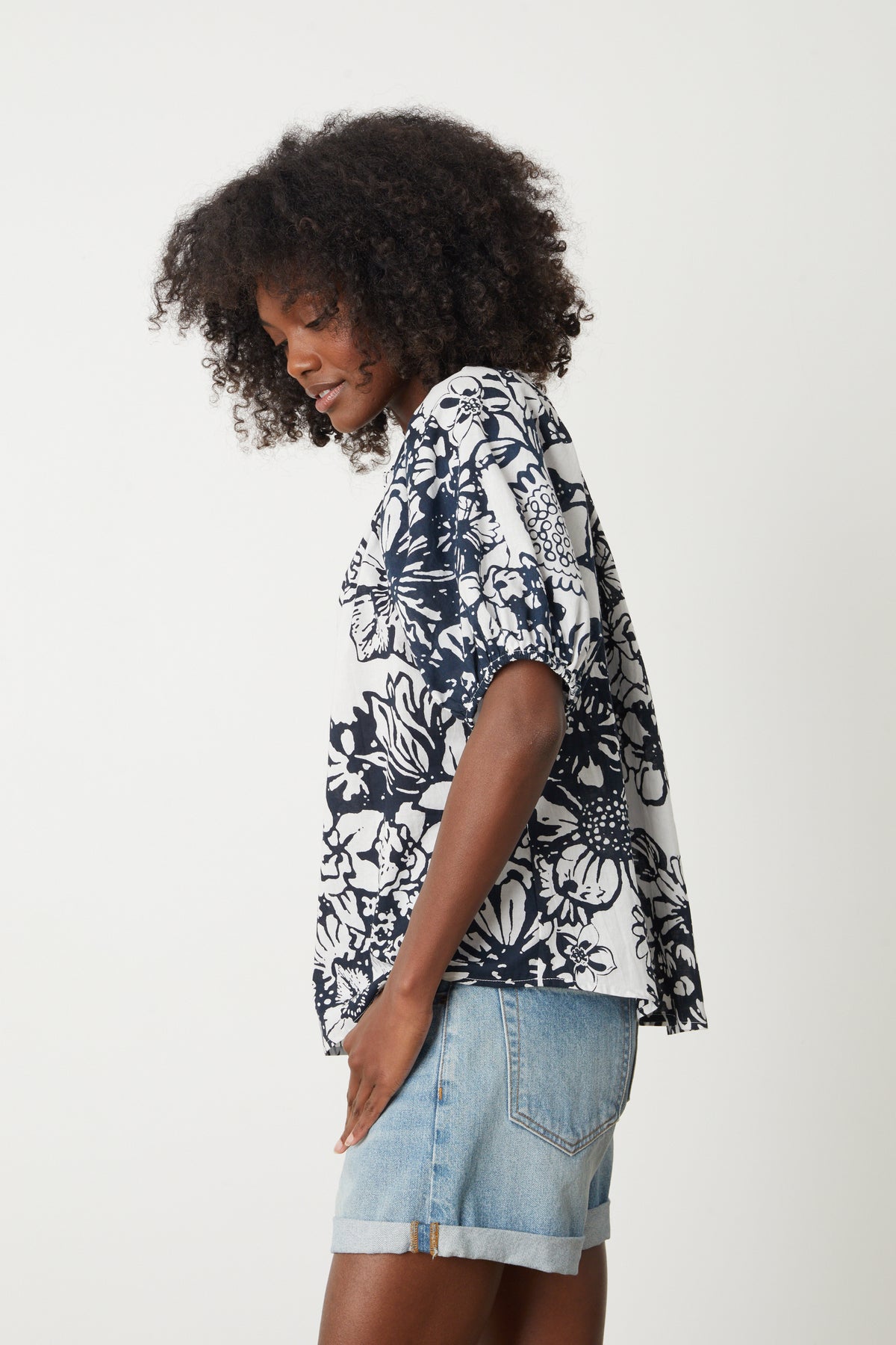   A woman wearing the Velvet by Graham & Spencer Angela Printed Boho Top and denim shorts. 