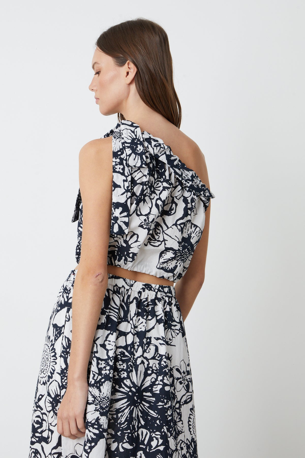 The back view of a woman in a Velvet by Graham & Spencer CAMILLA PRINTED ONE SHOULDER TOP.-26774829465793