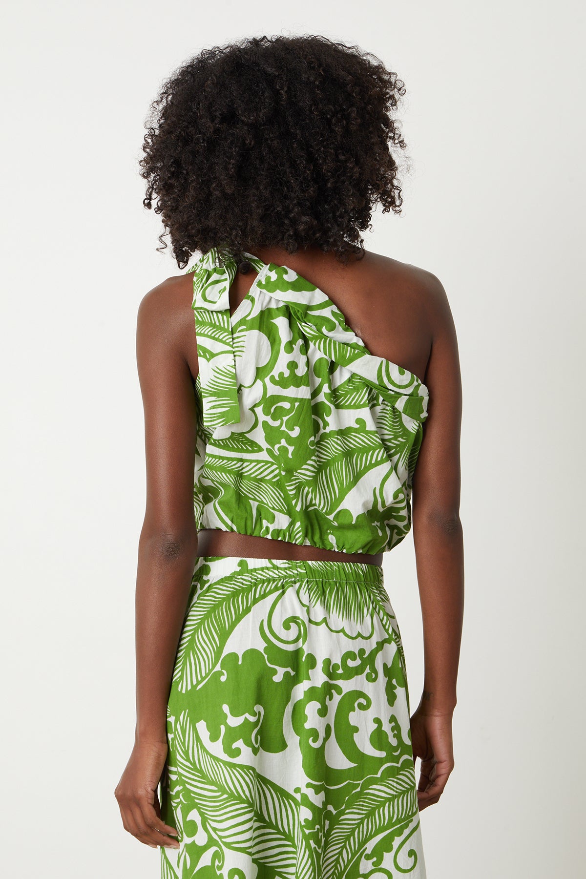   the back view of a woman in a Velvet by Graham & Spencer CAMILLA PRINTED ONE SHOULDER TOP dress. 