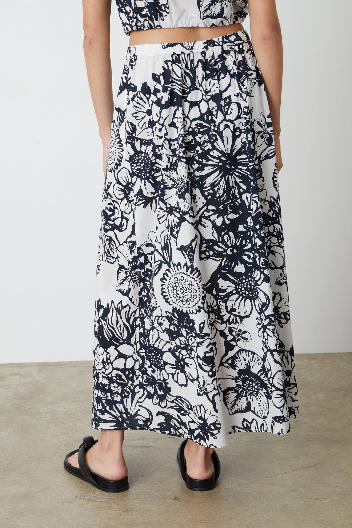   The back view of a person wearing a Velvet by Graham & Spencer Juliana Printed Maxi Skirt. 