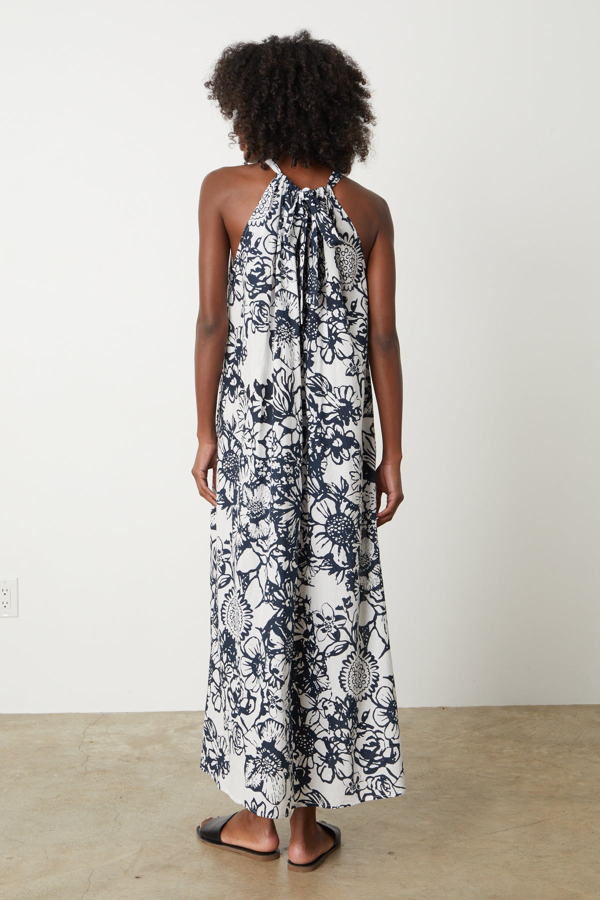 The back view of a woman wearing a black and white floral Velvet by Graham & Spencer Penelope Printed Maxi Dress.-26757320868033