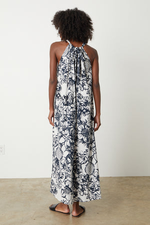 The back view of a woman wearing a black and white floral Velvet by Graham & Spencer Penelope Printed Maxi Dress.