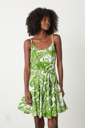 A woman wearing the Velvet by Graham & Spencer VIVIAN PRINTED DRESS, a green and white Hawaiian print dress.
