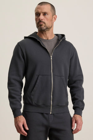 A man in the Velvet by Graham & Spencer BRADFORD HOODIE and matching pants stands against a plain light background, looking slightly to the side.