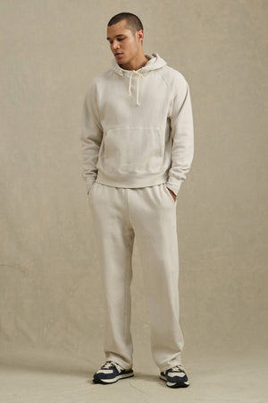 A man in the BRODIE HOODIE by Velvet by Graham & Spencer, paired with sweatpants.