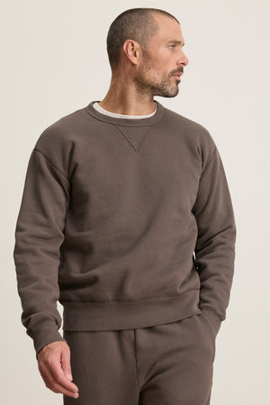 A man with short hair and a beard wears the CILLIAN SWEATSHIRT by Velvet by Graham & Spencer and matching pants, looking to his right against a plain background.
