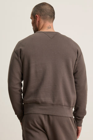 A man with short hair and a bird tattoo on his neck is seen from behind wearing the CILLIAN SWEATSHIRT by Velvet by Graham & Spencer, styled in a relaxed fit with matching pants.