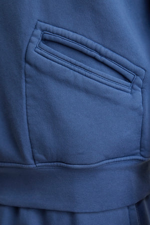 Close-up of the LEVI SWEATSHIRT by Velvet by Graham & Spencer in blue heavyweight fleece, featuring a single side pocket with a diagonal opening and visible stitching.