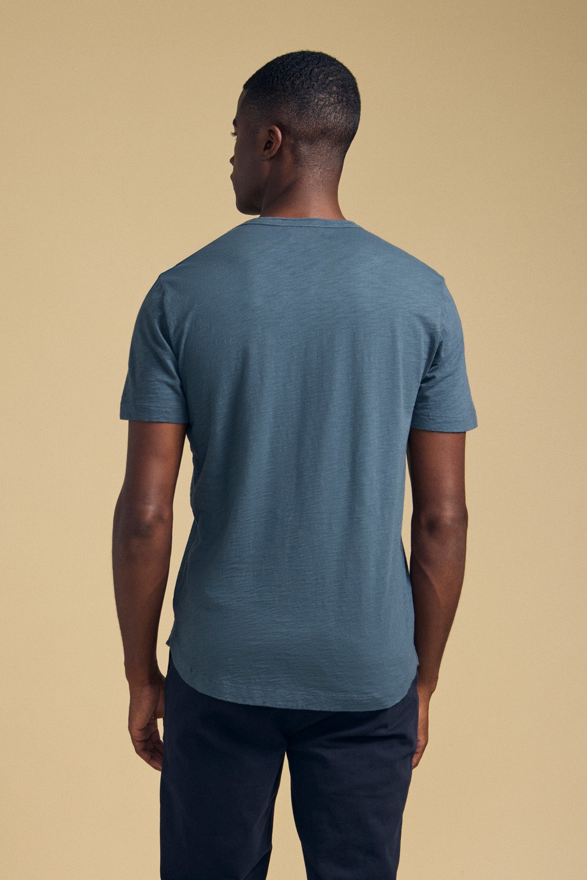 Back view of a person wearing a blue, short-sleeved, crew-neck AMARO TEE by Velvet by Graham & Spencer made of Peruvian cotton.-46288217047233