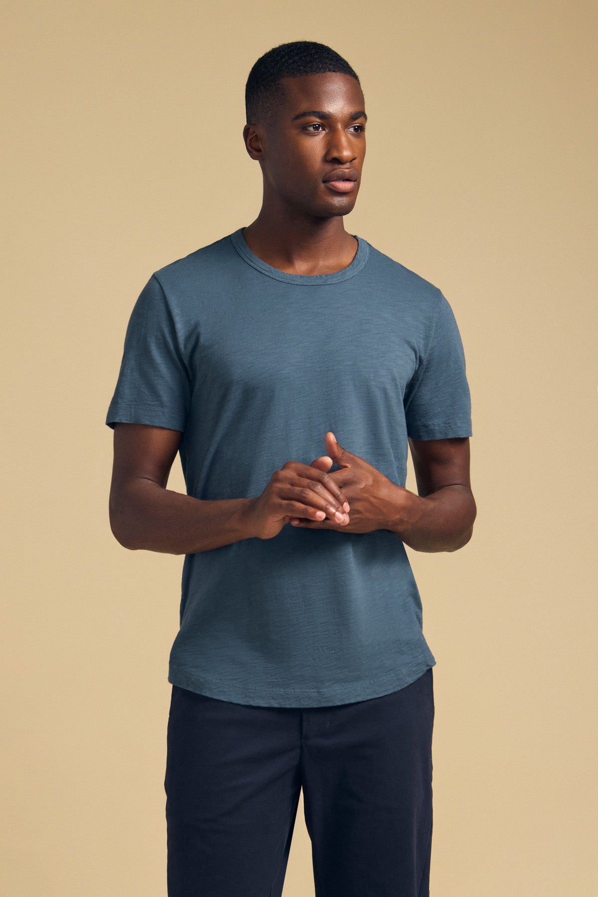 Front view of a men’s cotton slub tee showcasing short sleeves and a crew neckline on a model against a tan background-46288216981697