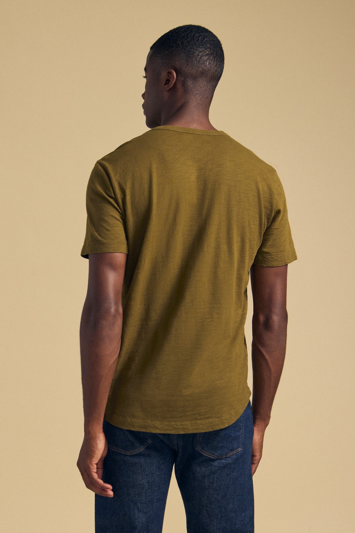 Back view of a person wearing an olive green short-sleeved Velvet by Graham & Spencer AMARO TEE and blue jeans.-46288219439297