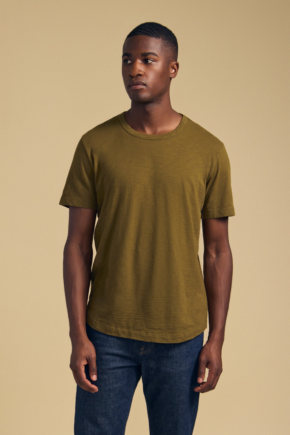 A man wearing an olive green AMARO TEE in Peruvian cotton with a crew neckline and blue jeans.-46288219340993