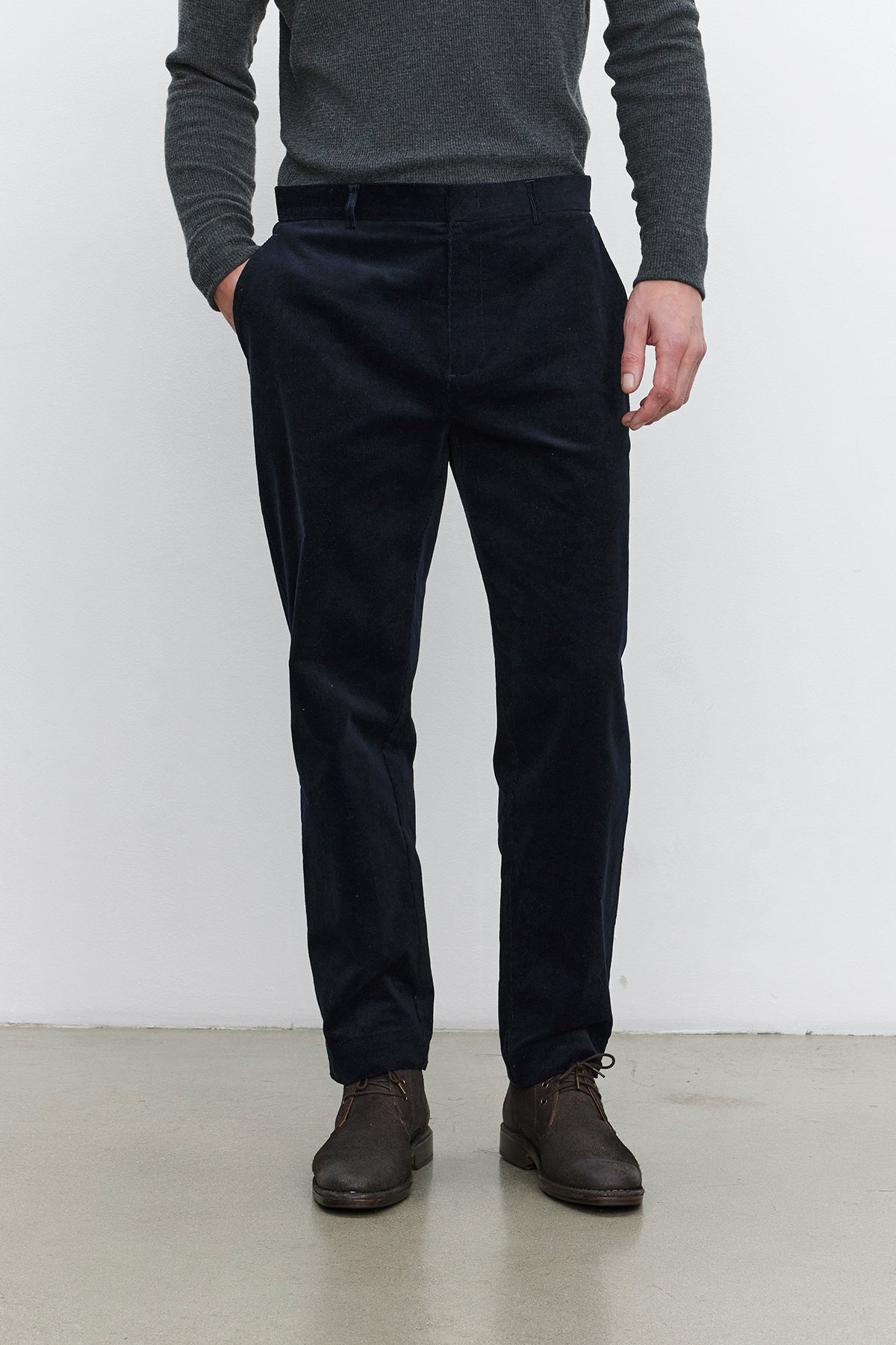   A person standing, wearing a dark gray long-sleeve shirt, the KRYSTOF CORDUROY PANT by Velvet by Graham & Spencer, and dark brown shoes. 