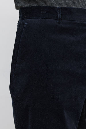 Close-up view of a person dressed in the KRYSTOF CORDUROY PANT by Velvet by Graham & Spencer and a tucked-in grey shirt.