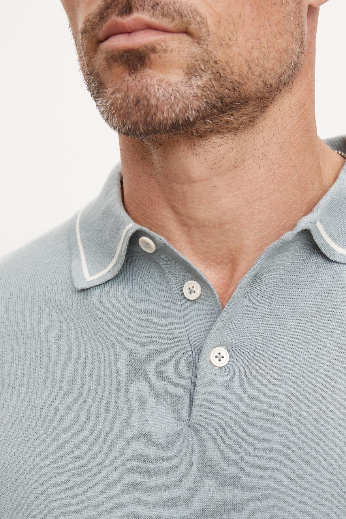   Close-up of a man wearing a gray Velvet by Graham & Spencer Shepard Polo with a three-button placket and collar detailing, focusing on the neckline and lower face. 