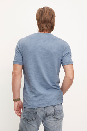 The back of a man wearing Velvet by Graham & Spencer jeans and a blue t - shirt.