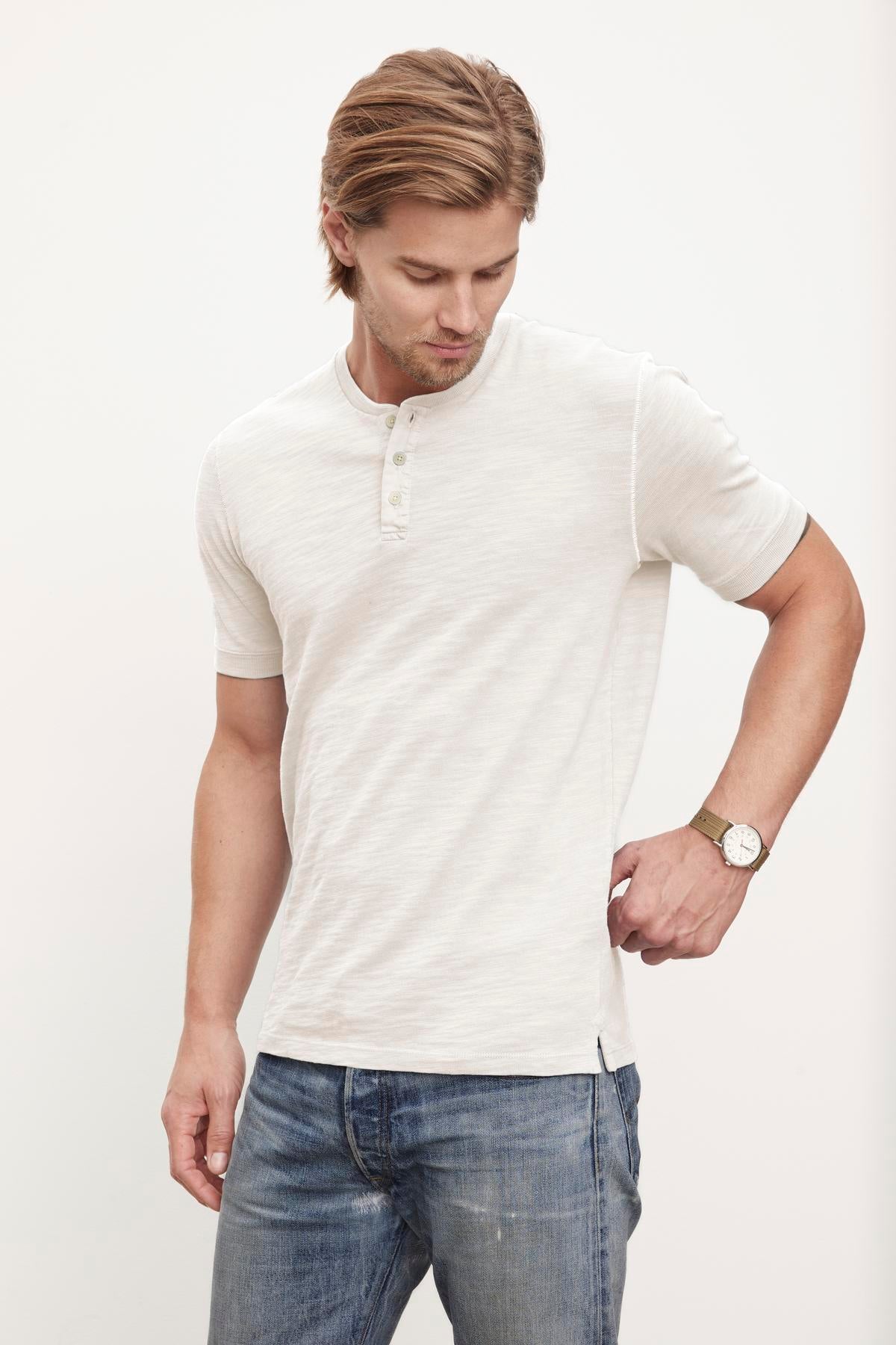   A man wearing jeans and a white Velvet by Graham & Spencer VITO HENLEY shirt. 