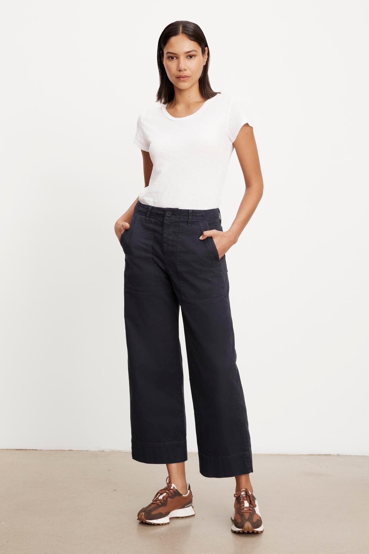 A woman standing in a neutral pose wearing a white t-shirt, Velvet by Graham & Spencer MYA COTTON CANVAS PANT wide-leg pants, and brown lace-up shoes.-36320657440961