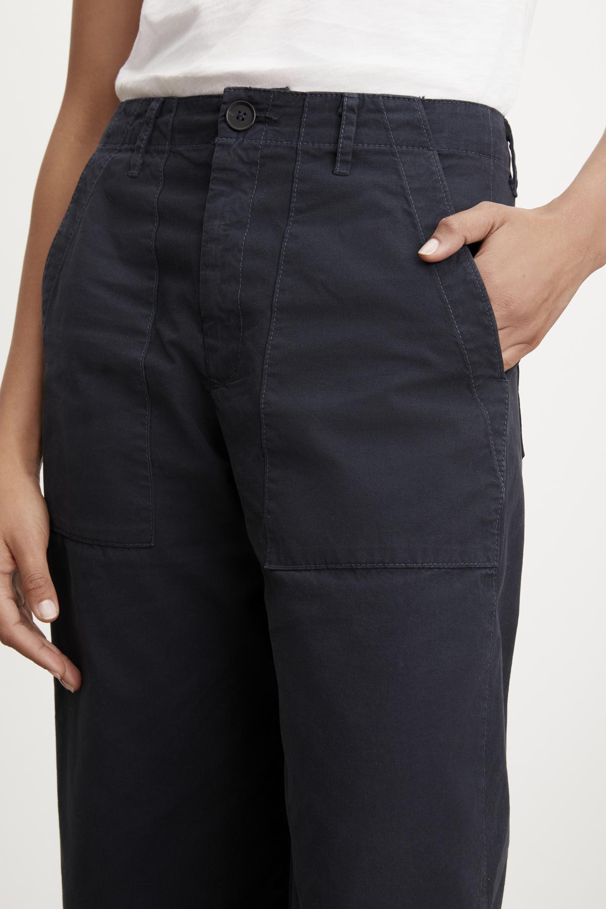 Close-up of a person wearing black Velvet by Graham & Spencer MYA COTTON CANVAS PANT with a hand in the pocket.-36320657539265