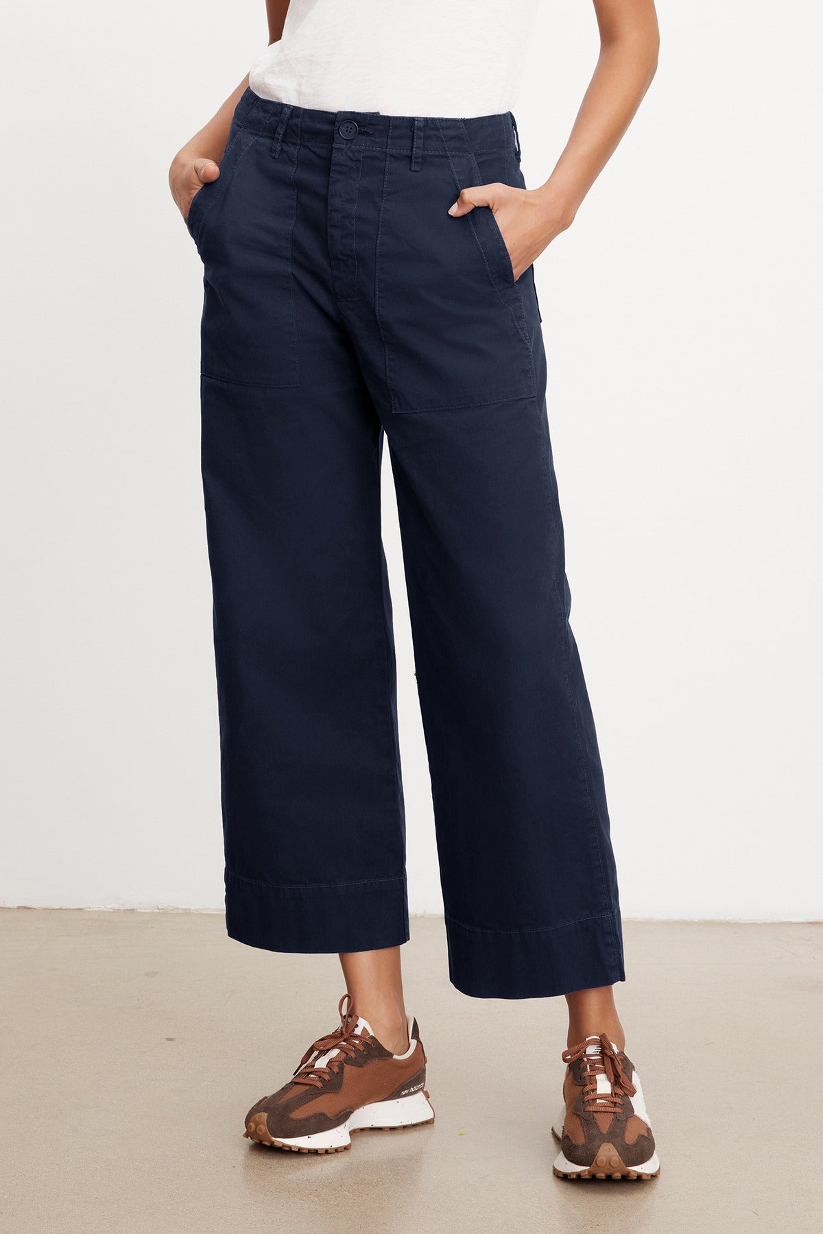 A person wearing navy blue Velvet by Graham & Spencer MYA COTTON CANVAS PANTS and a white shirt paired with brown and white sneakers, standing in a neutral pose against a plain background.-37628822421697