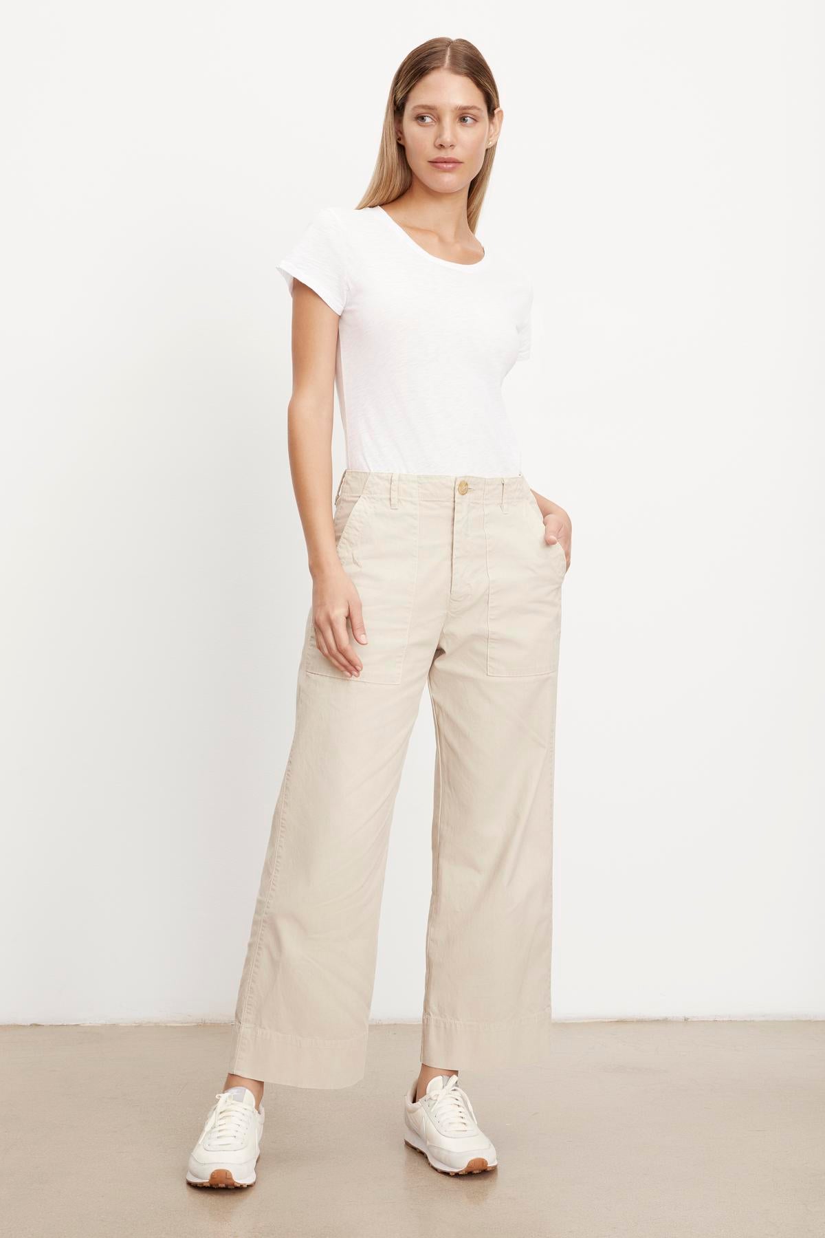   The model is wearing a slim white t-shirt and Velvet by Graham & Spencer MYA COTTON CANVAS PANT in beige. 