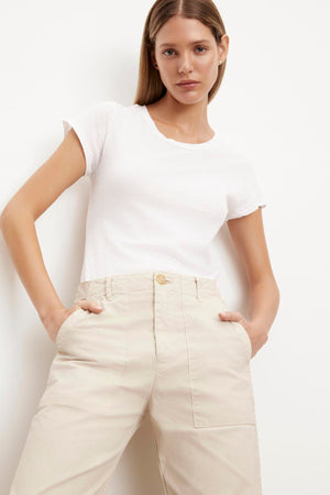 The model is wearing a white t-shirt with beige cargo pants made of Velvet by Graham & Spencer's MYA COTTON CANVAS PANT.