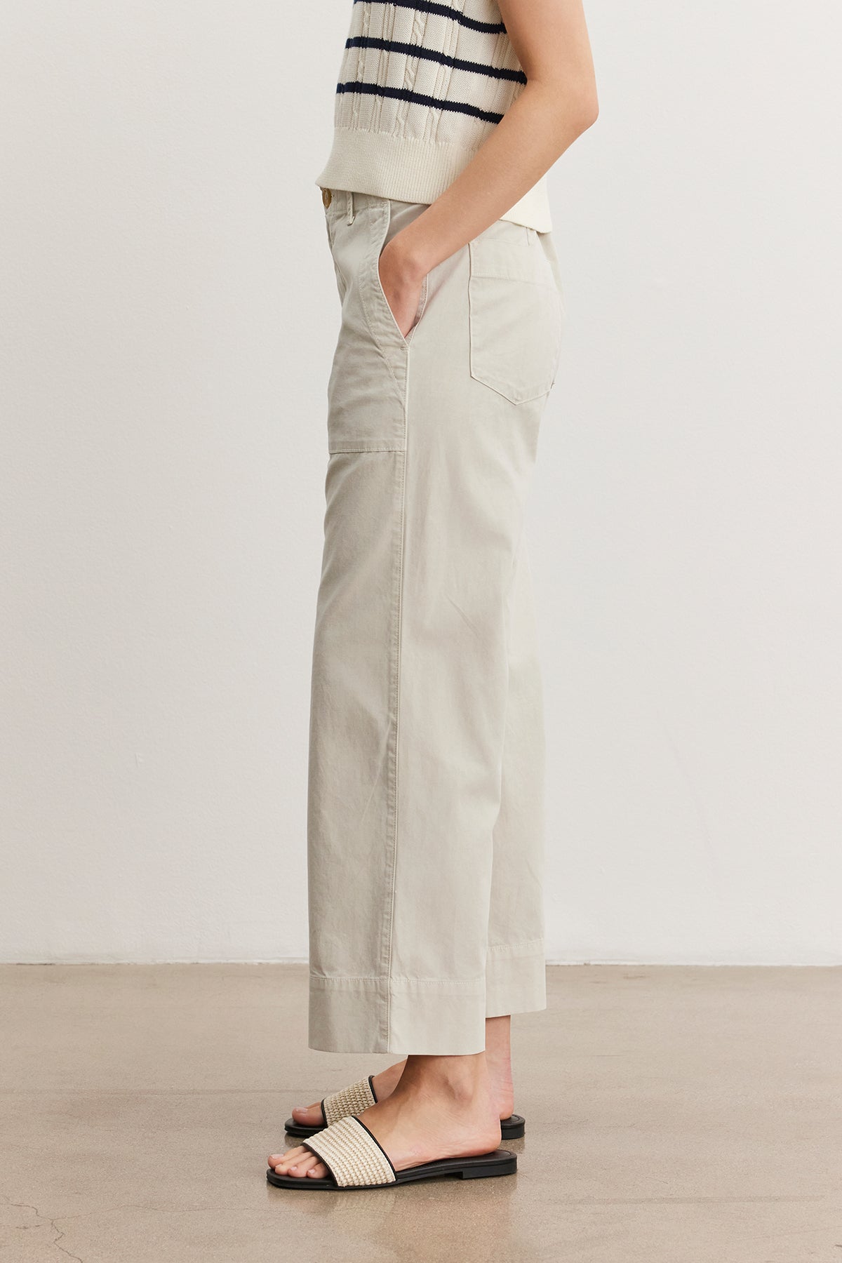 A woman standing in a neutral pose wearing a striped tank top, light gray Velvet by Graham & Spencer MYA COTTON CANVAS PANTS, and black slide sandals. Only the lower half of her body is visible.-37628822257857