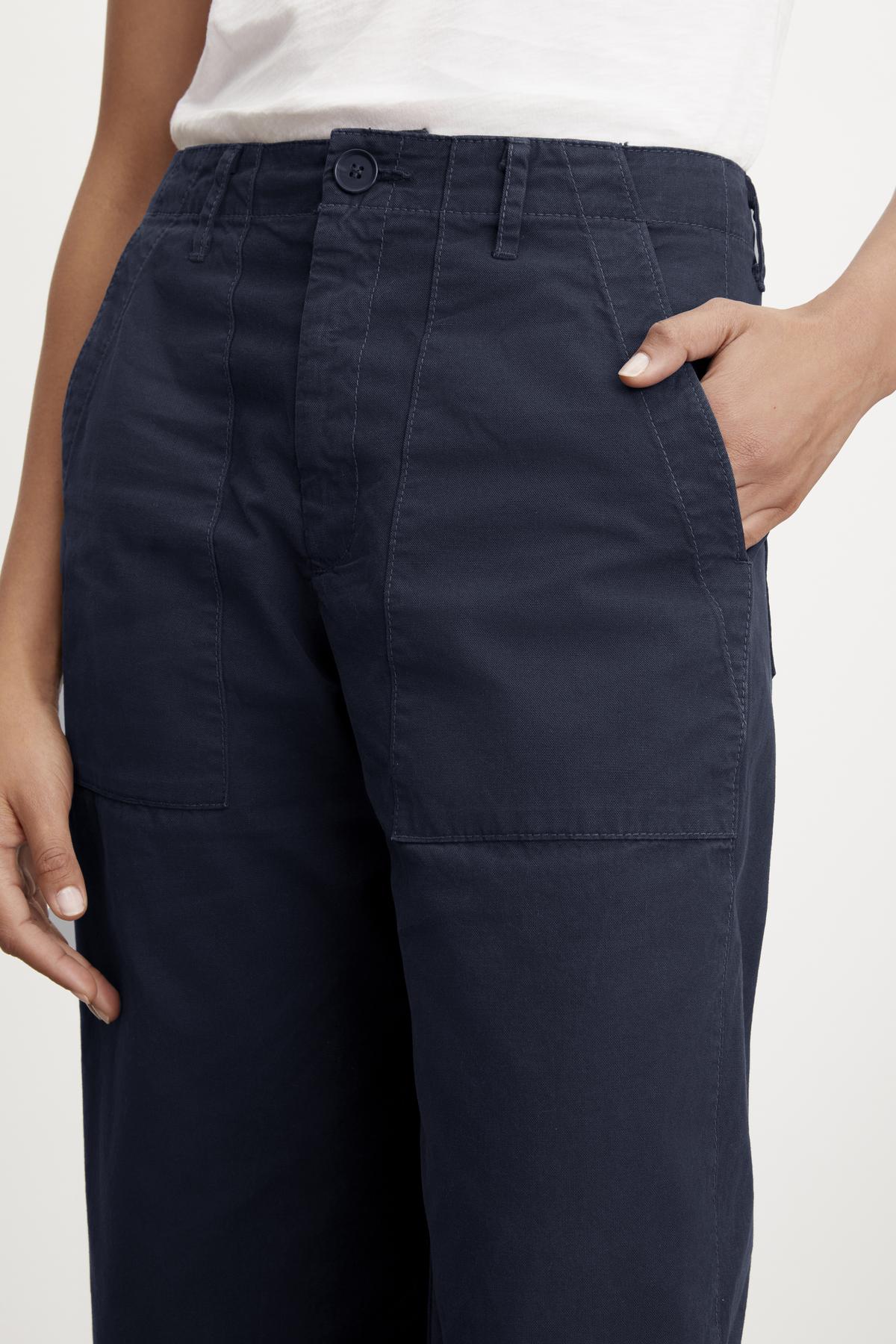   Close-up of a woman's hand touching the pocket of MYA COTTON CANVAS PANTS by Velvet by Graham & Spencer, highlighting the stitching and fabric texture. 