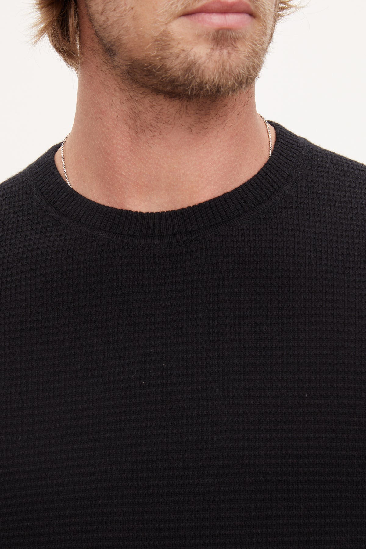   A man with long hair wearing a black Velvet by Graham & Spencer cashmere sweater. 