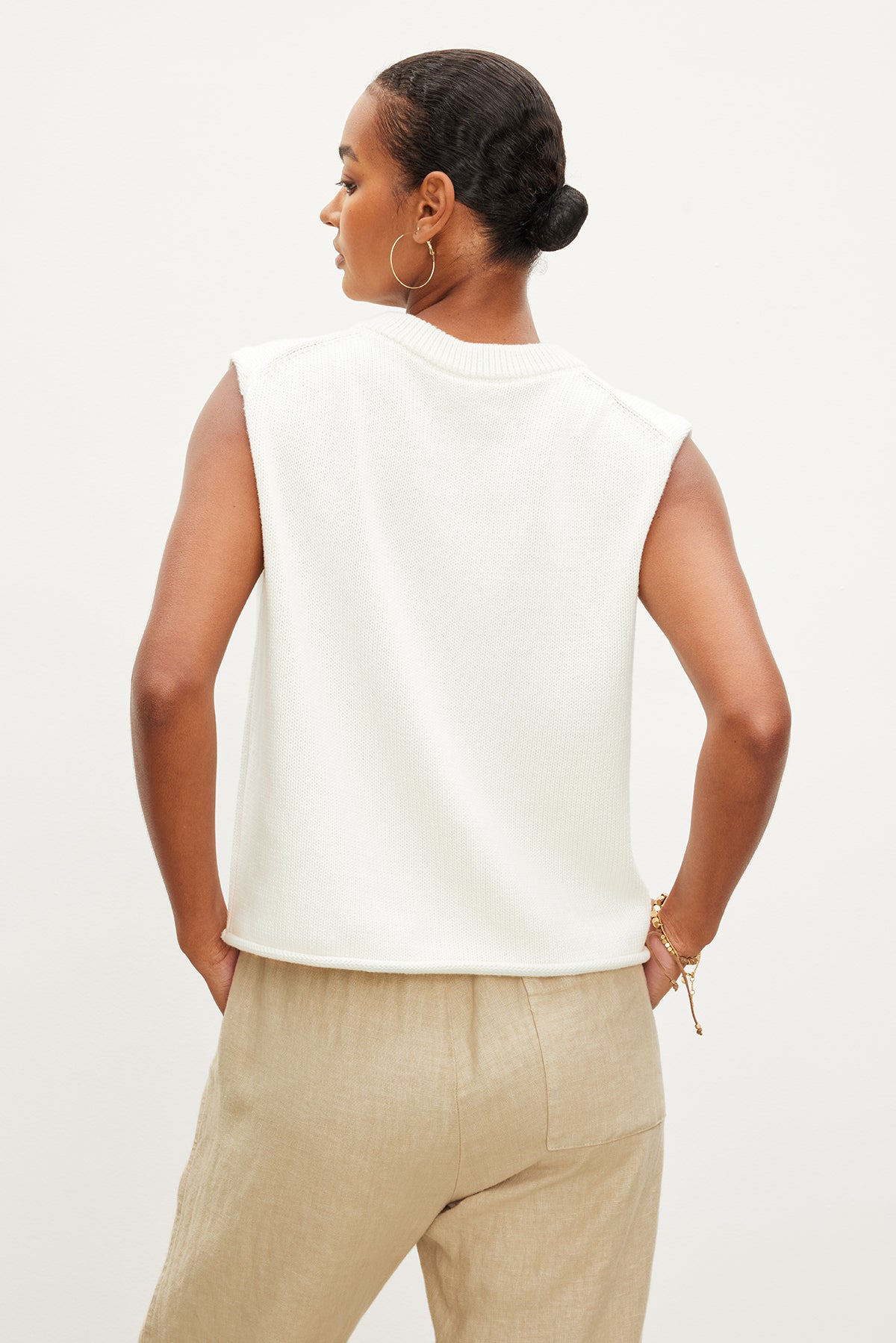   The back view of a woman wearing a Velvet by Graham & Spencer ASTER CREW NECK SWEATER and tan pants. 