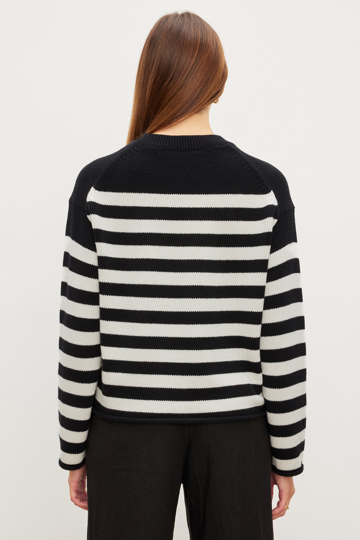 The modern silhouette of a woman wearing a Velvet by Graham & Spencer LEX STRIPED CREW NECK SWEATER.-35967621890241
