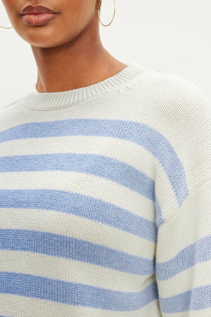 A woman wearing a modern blue and white striped LEX STRIPED CREW NECK SWEATER by Velvet by Graham & Spencer.