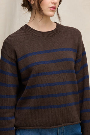 A person wearing the LUCIA COTTON CASHMERE SWEATER by Velvet by Graham & Spencer—a relaxed-fit brown crewneck with horizontal navy stripes—paired with blue jeans, shown from shoulders to waist.