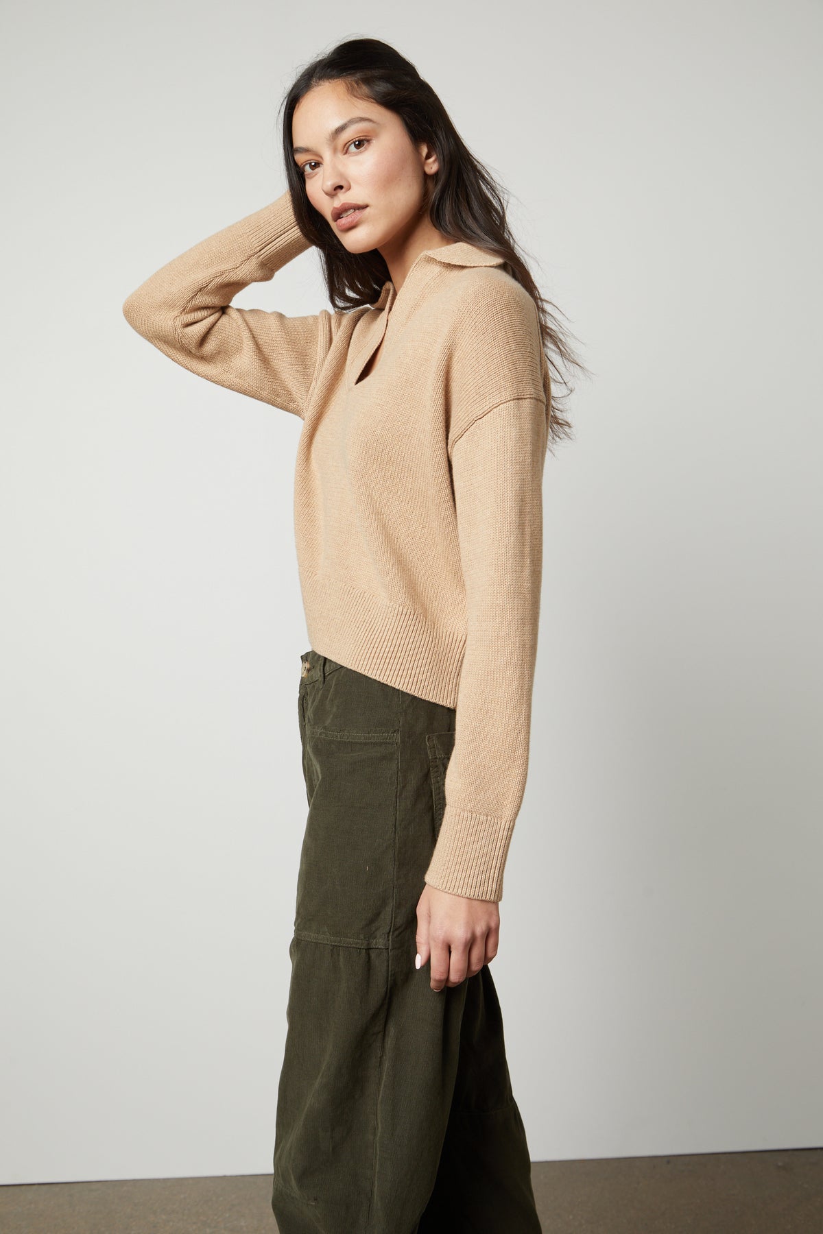   The model is wearing a cotton/cashmere blend LUCIE POLO SWEATER by Velvet by Graham & Spencer layered with olive trousers. 