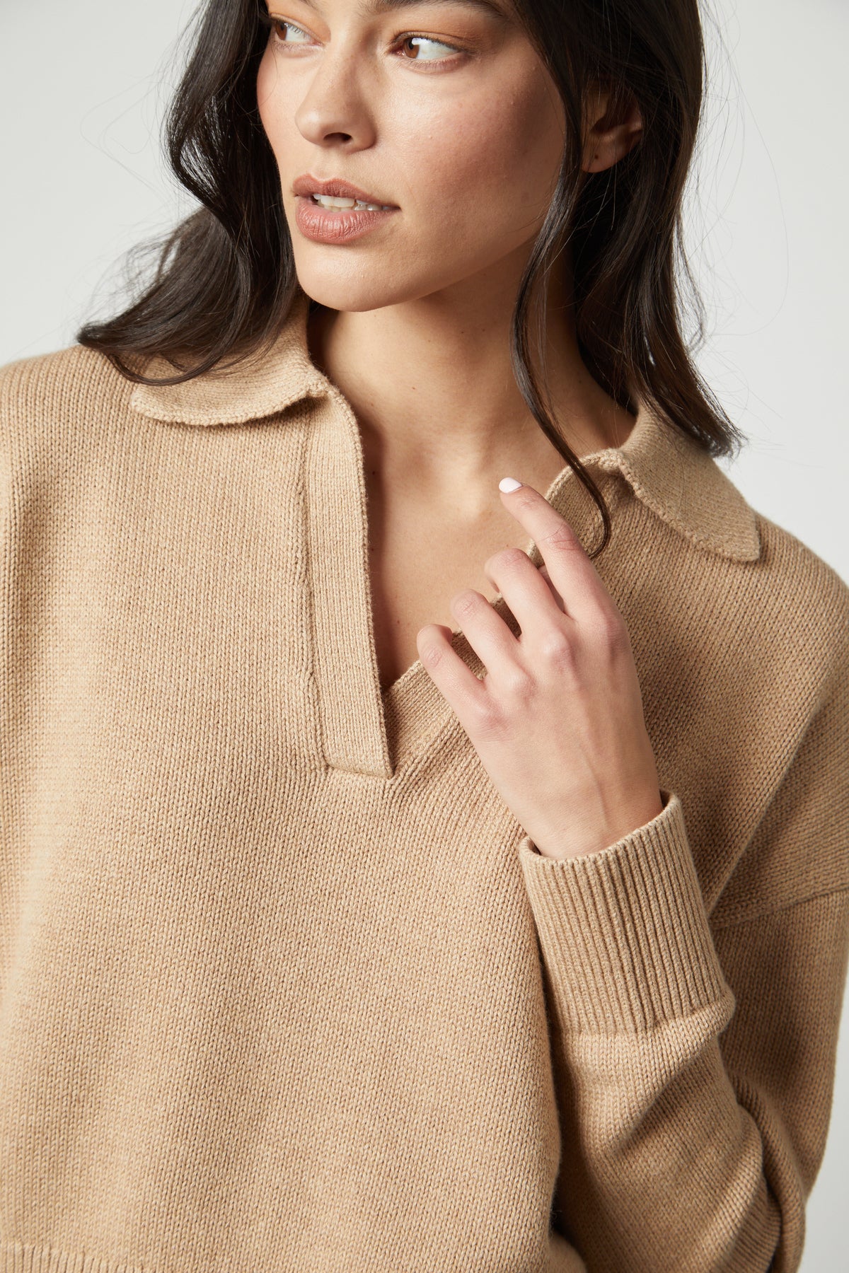   The model is wearing a layered LUCIE POLO SWEATER by Velvet by Graham & Spencer with a ribbed V-neckline. 