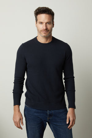 A man wearing a Velvet by Graham & Spencer Walter Crew Neck Sweater and jeans.