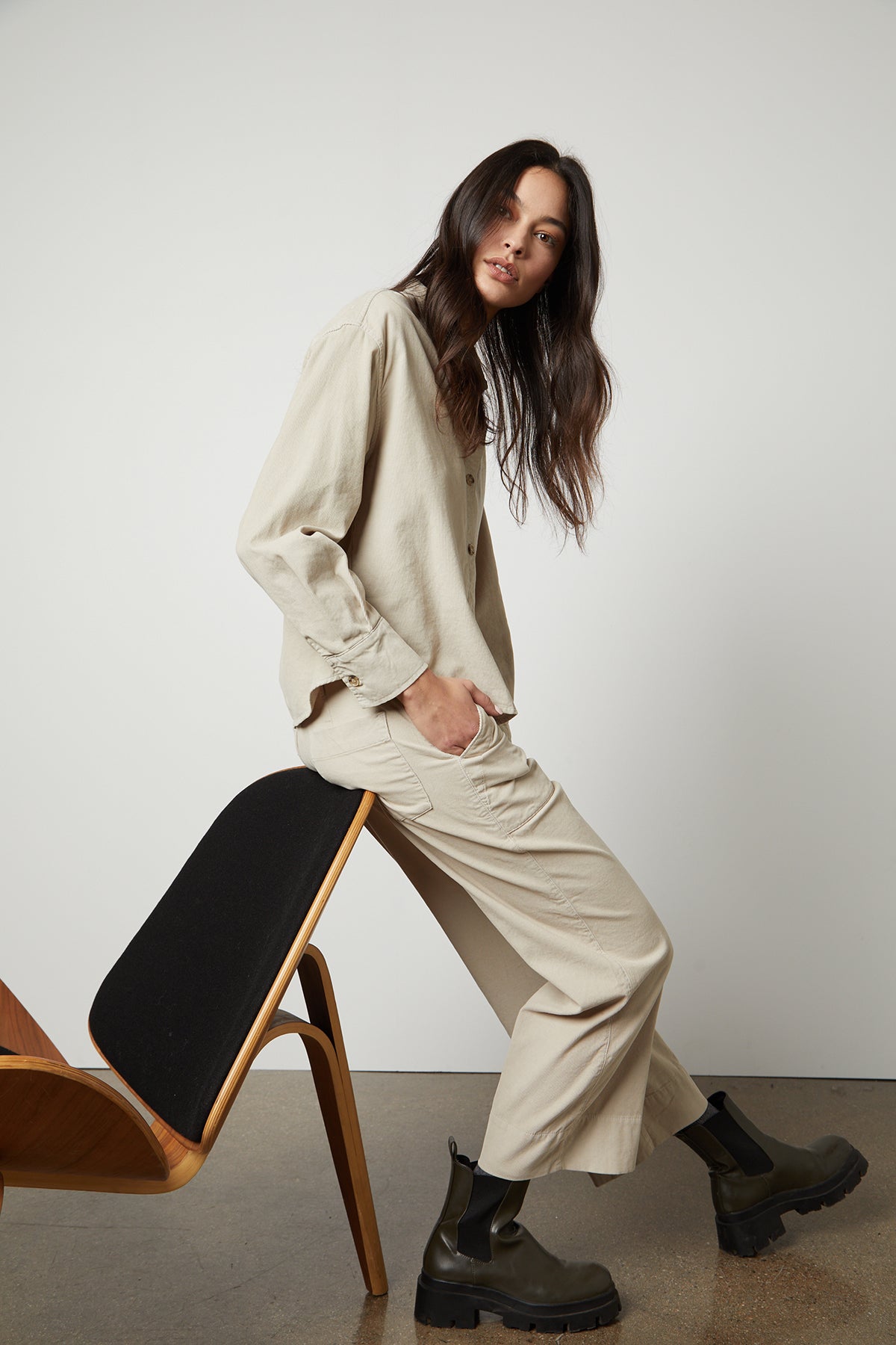   A woman is sitting on a chair in a Velvet by Graham & Spencer VERA CORDUROY WIDE LEG PANT shirt and pants. 