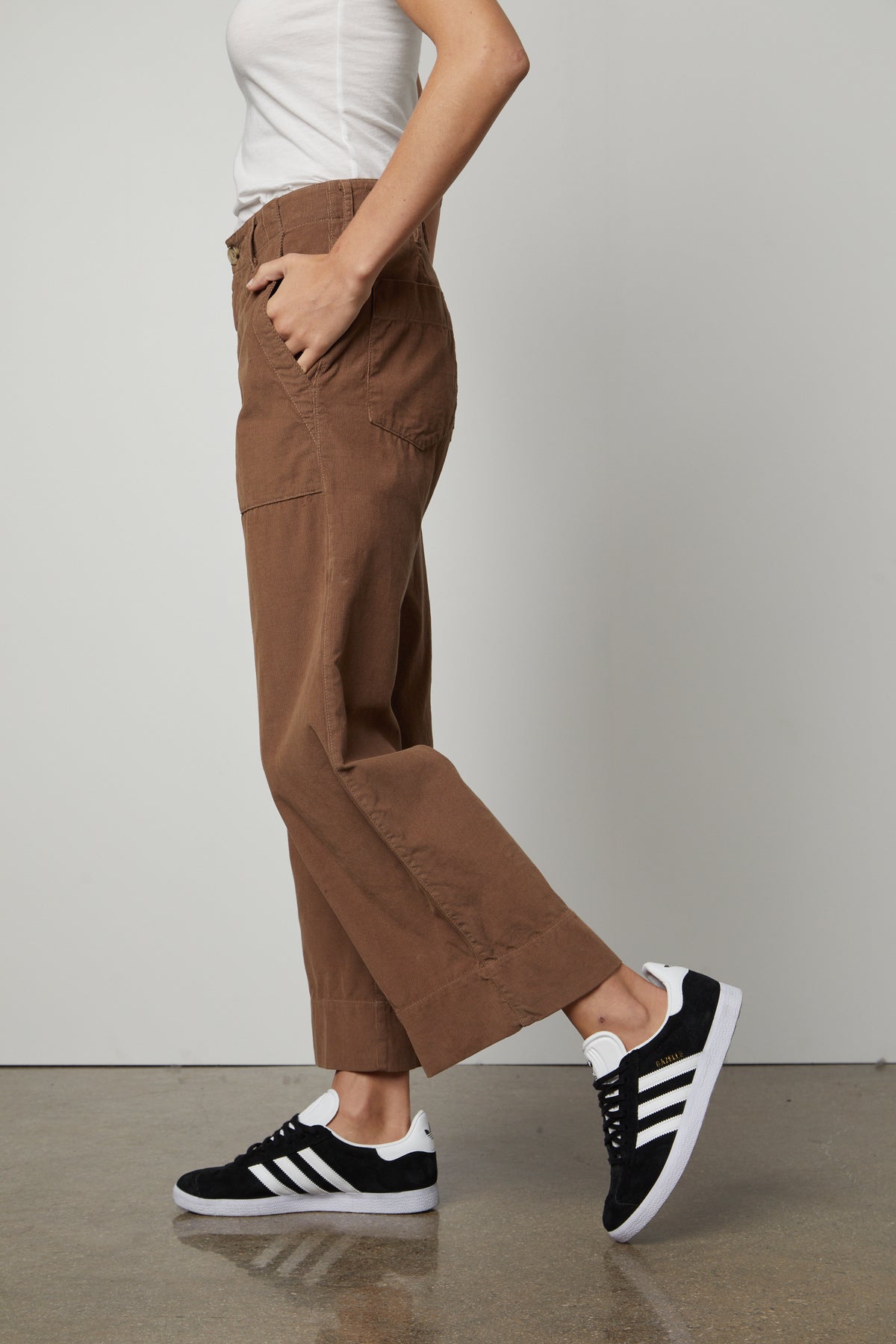   A woman wearing a pair of Velvet by Graham & Spencer VERA CORDUROY WIDE LEG PANT and sneakers. 