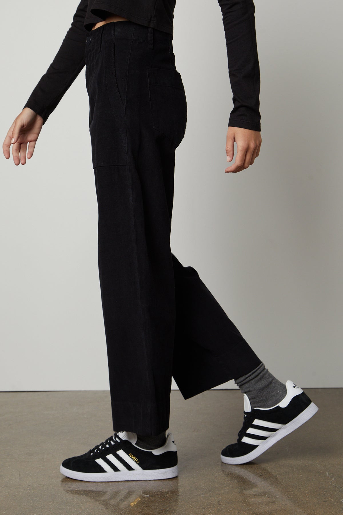 A woman wearing VERA CORDUROY WIDE LEG PANTS by Velvet by Graham & Spencer and sneakers.-26861576454337