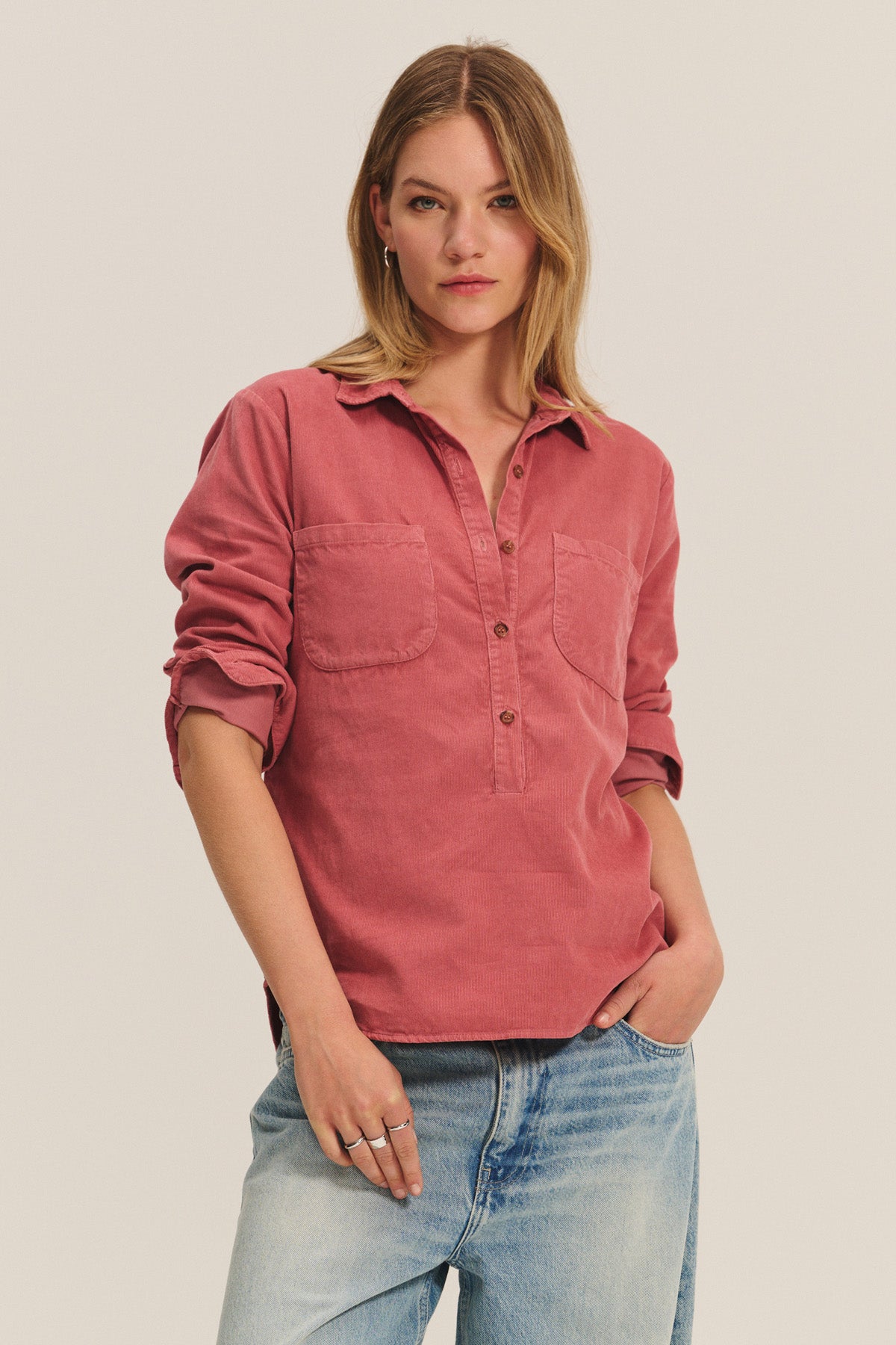 Model wears the ARIELLE CORDUROY SHIRT by Velvet by Graham & Spencer in faded red with two chest pockets, paired with light blue jeans—a stylish fall essential.-40328512176321
