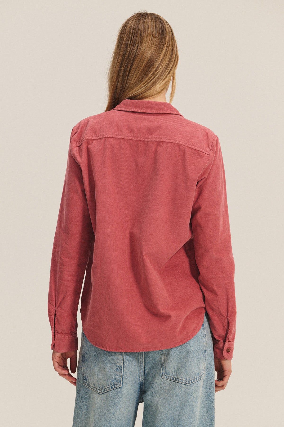 A person with long light brown hair, seen from behind against a plain background, wears the ARIELLE CORDUROY SHIRT by Velvet by Graham & Spencer with light blue jeans—a fall essential.-40328512143553