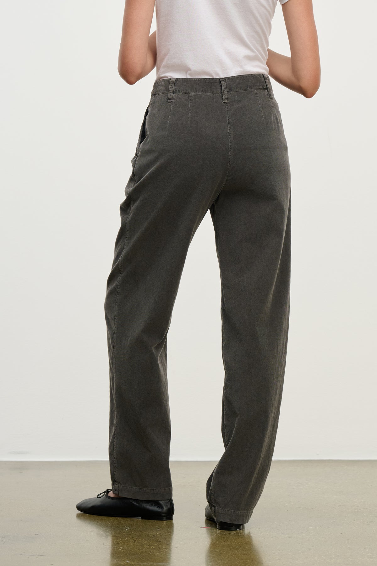 A person stands with their back to the camera on a polished floor, wearing a white t-shirt and Velvet by Graham & Spencer’s GAIL CORDUROY PANT— a relaxed, high-waisted, straight-leg cotton corduroy trouser.-39800318099649